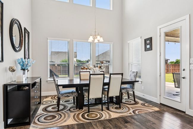 Dining area with a towering ceiling, a chandelier, and wood finished floors | Image 10
