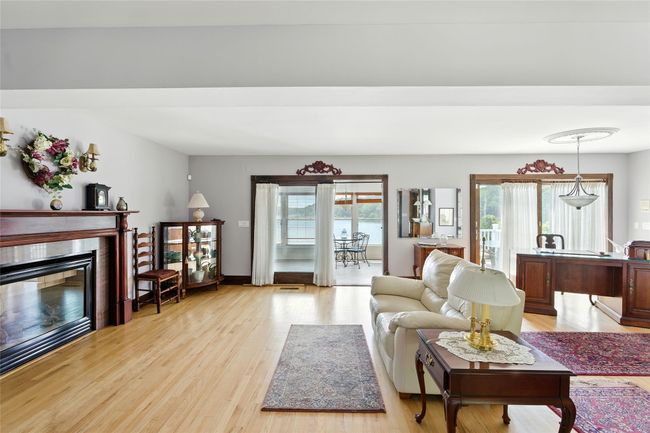 Living area with a glass covered fireplace and light wood finished floors | Image 24