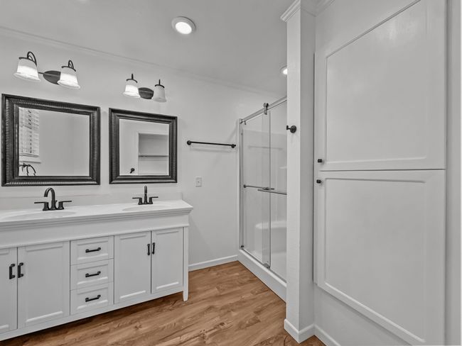 Bathroom with a stall shower, double vanity, wood finished floors, and ornamental molding | Image 10