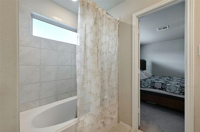 Full bath featuring shower / bath combo with shower curtain, ensuite bathroom, and tile patterned floors | Image 7