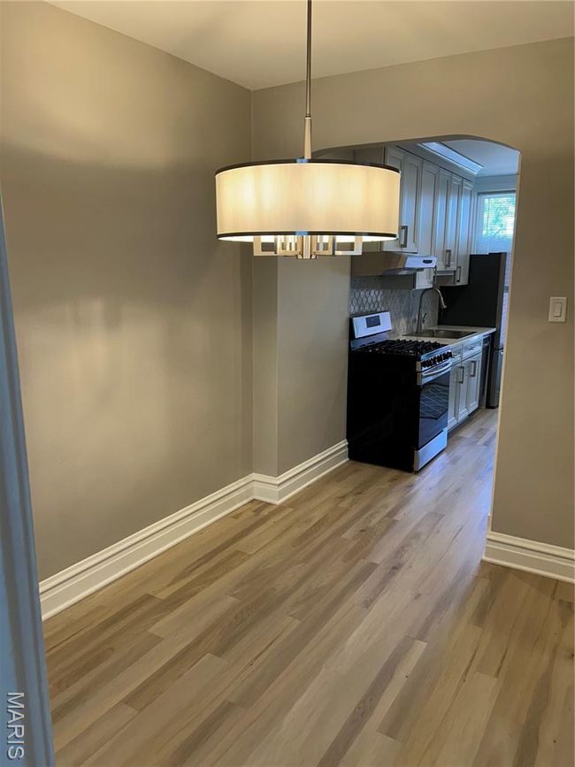 Kitchen with range, light wood-style floors, tasteful backsplash, arched walkways, and exhaust hood | Image 9
