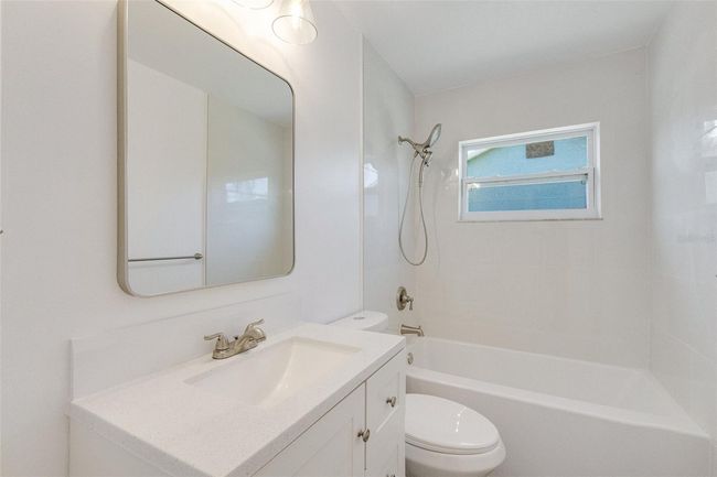 The hall bath is fully updated with fresh tile, a new vanity, and designer fixtures | Image 11