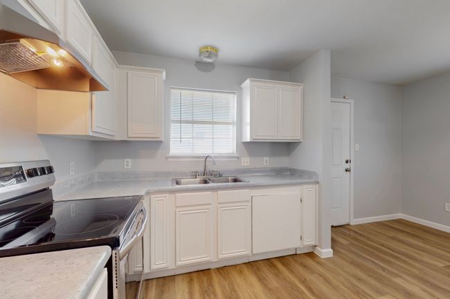 Kitchen with white cabinets, a sink, light wood-type flooring, stainless steel electric range, and range hood | Image 27