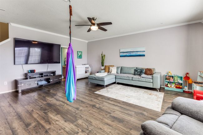 Living room featuring ceiling fan, ornamental molding, wood finished floors, and baseboards | Image 7