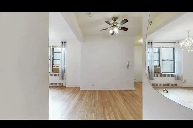 Spare room with radiator, light wood-type flooring, ceiling fan, and a chandelier | Image 4