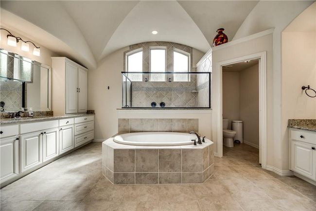 Full bathroom featuring vanity, a bath, lofted ceiling, toilet, and a tile shower | Image 10