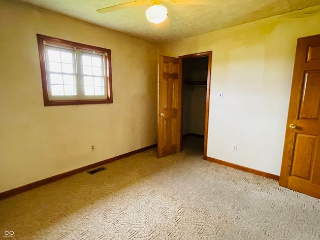 unfurnished bedroom with a spacious closet, light colored carpet, baseboards, a textured ceiling, and a closet | Image 19