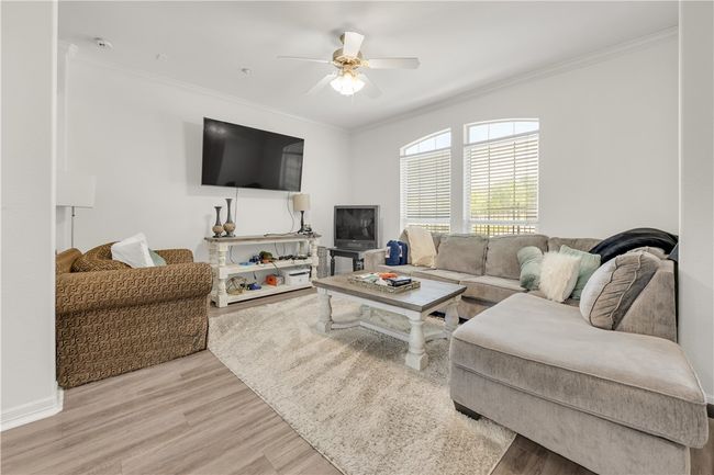 Living area with light wood-style floors, ornamental molding, and ceiling fan | Image 5