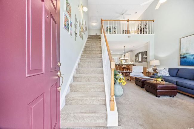 Entryway with carpet floors, a towering ceiling, stairway, crown molding, and a ceiling fan | Image 4