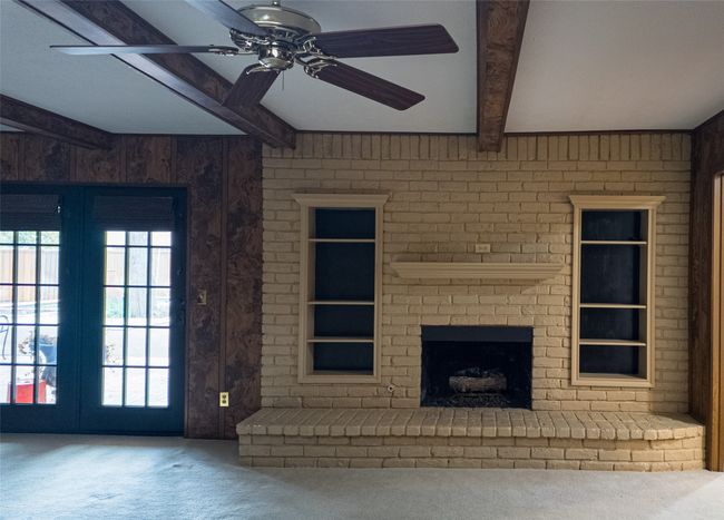 Unfurnished living room featuring a brick fireplace, ceiling fan, beamed ceiling, and carpet floors | Image 19