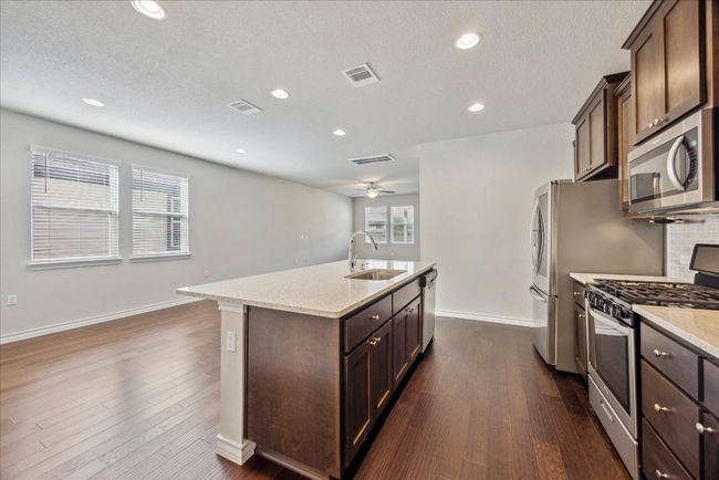 Kitchen with a sink, an island with sink, stainless steel appliances, baseboards, and visible vents | Image 7