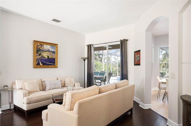 Beautiful living room upon entry into the home with sliding door revealing the beautiful pool lanai and tropical Florida backdrop. | Image 15