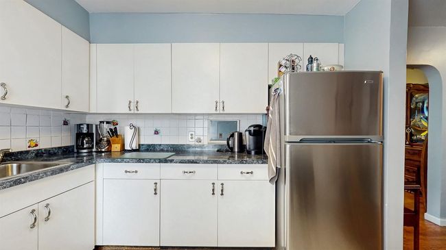 Kitchen with freestanding refrigerator, decorative backsplash, and dark countertops | Image 12