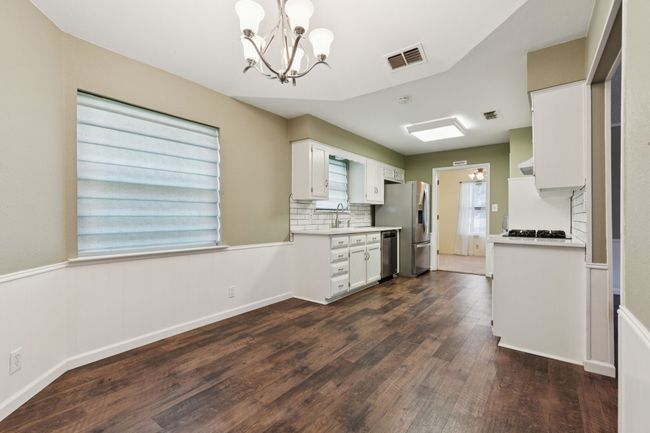 Kitchen with stainless steel appliances, a chandelier, light countertops, and dark wood-type flooring | Image 14