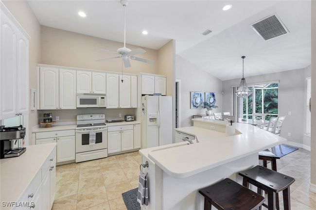 Kitchen featuring pendant lighting, white cabinetry, white appliances, and a kitchen island with sink | Image 8