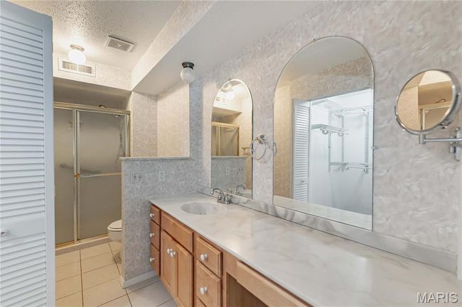 Bathroom featuring tile patterned flooring, a shower stall, a closet, a textured ceiling, and vanity | Image 34