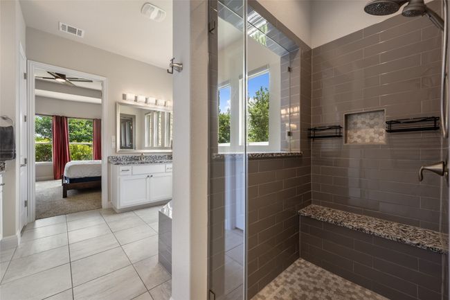 Ensuite bathroom featuring a tile shower, ceiling fan, vanity, and tile patterned flooring | Image 30