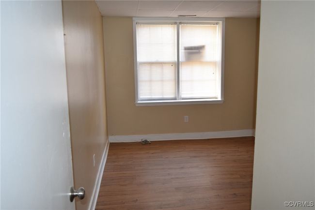 Empty room with wood finished floors, baseboards, and a drop ceiling | Image 8