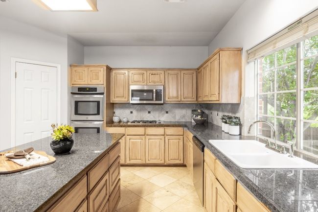 Kitchen with appliances with stainless steel finishes, a sink, light brown cabinets, and backsplash | Image 16