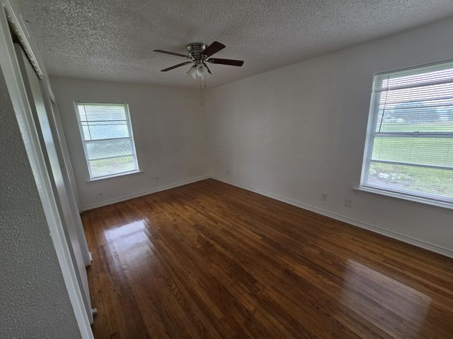Spare room with dark wood-style flooring, a textured ceiling, and a ceiling fan | Image 6