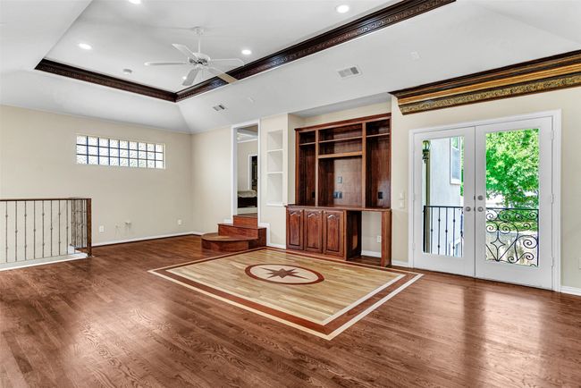 A built-in desk and entertainment area is flanked by built-in shelves and the double doors to the balcony overlooking the pool and backyard. The steps to the back of the room lead to two of the secondary bedrooms that share a jack & iill bath. | Image 29