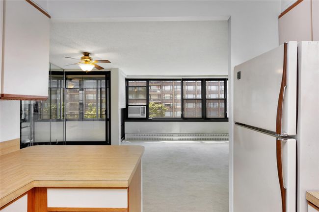 Kitchen with freestanding refrigerator, carpet, a ceiling fan, baseboard heating, and cooling unit | Image 6