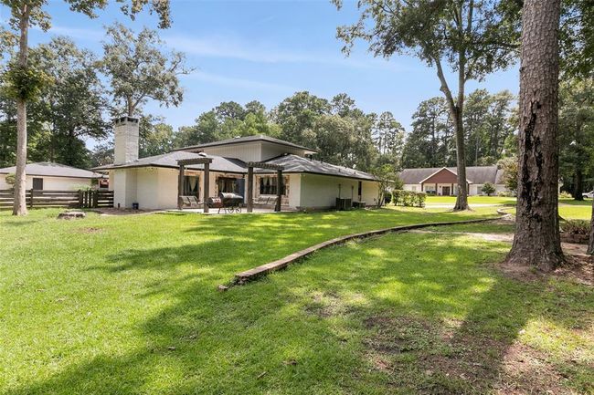 This photo showcases a charming single-story home with a spacious backyard, mature trees, and a cozy patio area, ideal for outdoor activities and relaxation. | Image 47