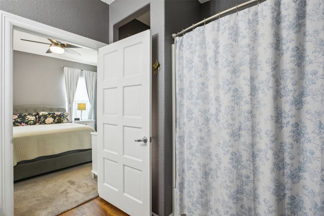 Full Primary bath with curtained shower, a textured wall, ceiling fan, wood plank laminate flooring. | Image 26