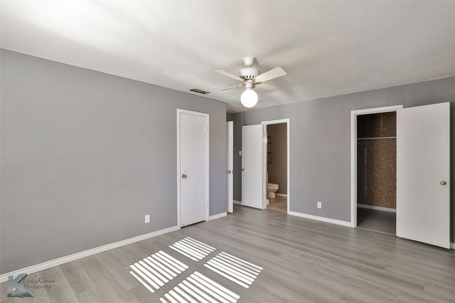 Unfurnished bedroom with a closet, light hardwood / wood-style floors, ensuite bath, and ceiling fan | Image 11