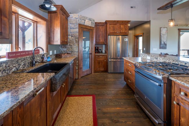 Kitchen featuring stainless steel appliances, a sink, dark wood-type flooring, stone countertops, and high vaulted ceiling | Image 14