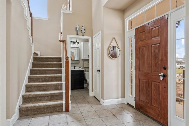 Foyer with a high ceiling, light tile patterned flooring, stairway, and baseboards | Image 5