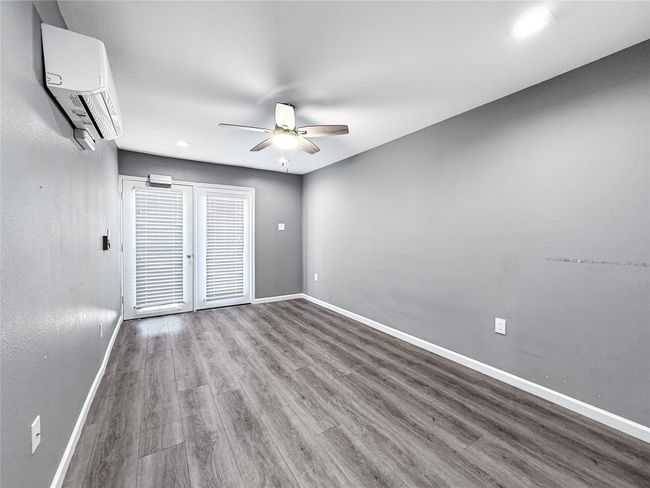 Empty room with wood finished floors, an AC wall unit, a ceiling fan, and recessed lighting | Image 26