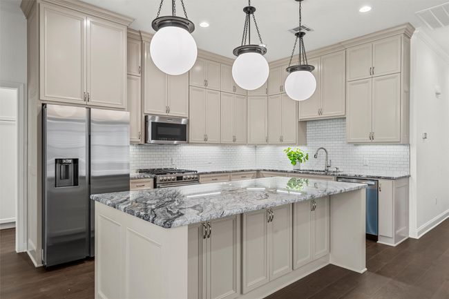 Kitchen with appliances with stainless steel finishes, dark wood-style flooring, light stone countertops, backsplash, and recessed lighting | Image 12