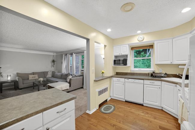 Kitchen featuring white dishwasher, radiator, stainless steel microwave, light wood-style floors, and open floor plan | Image 12