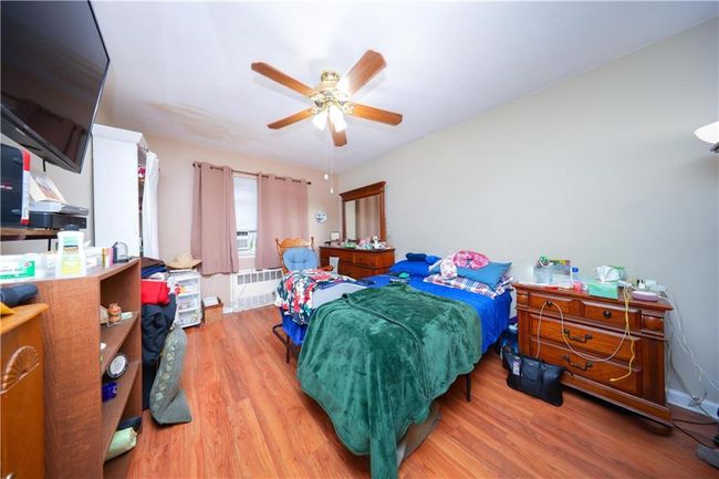 Bedroom with wood finished floors, radiator, and a ceiling fan | Image 19
