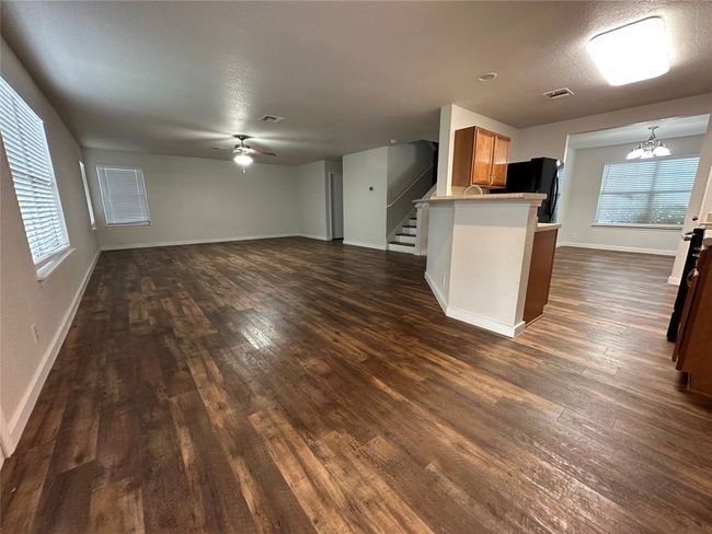 Kitchen with dark wood finished floors, a ceiling fan, freestanding refrigerator, a chandelier, and open floor plan | Image 6