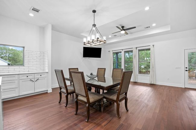 Dining room featuring dark wood-type flooring, recessed lighting, a ceiling fan, and a tray ceiling | Image 10