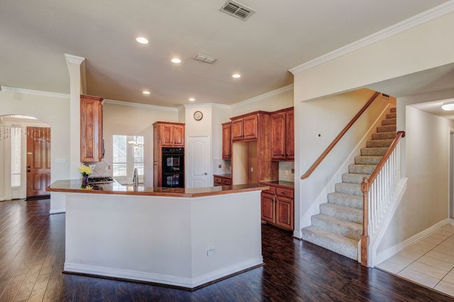Kitchen with dark hardwood / wood-style flooring, double oven, sink, ornamental molding, and kitchen peninsula | Image 21