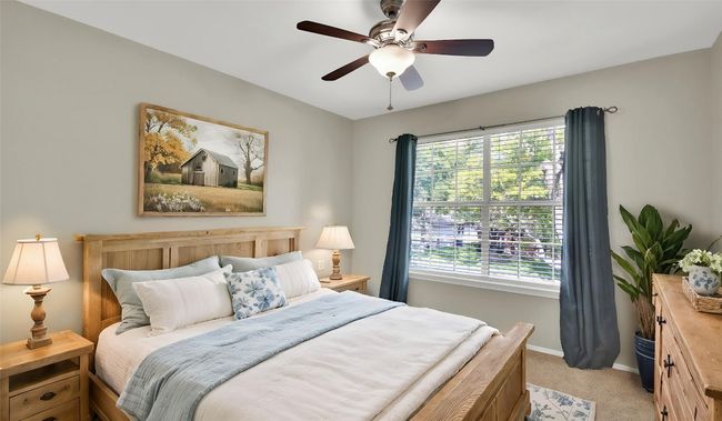 Ensuite bedroom with light colored carpet, baseboards, and a ceiling fan (virtually staged) | Image 15