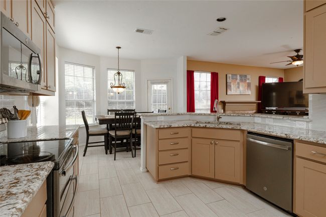 Kitchen featuring a sink, visible vents, ceiling fan with notable chandelier, and appliances with stainless steel finishes | Image 14
