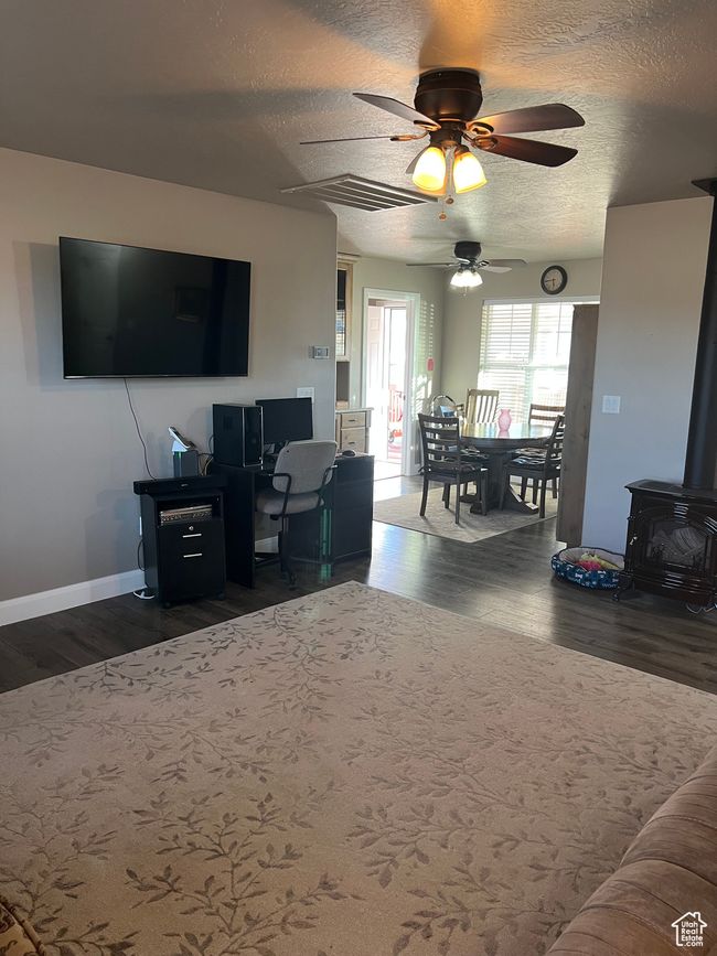 Living area with a wood stove, wood finished floors, a ceiling fan, and a textured ceiling | Image 34