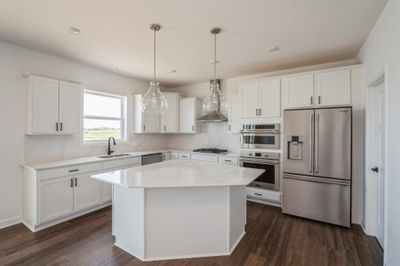 (Photo of a decorated model, actual homes finishes and colors will vary) The Sinclair features a stunning kitchen with a large center island, quartz countertops, LVP floors, stainless appliances and more. | Image 3