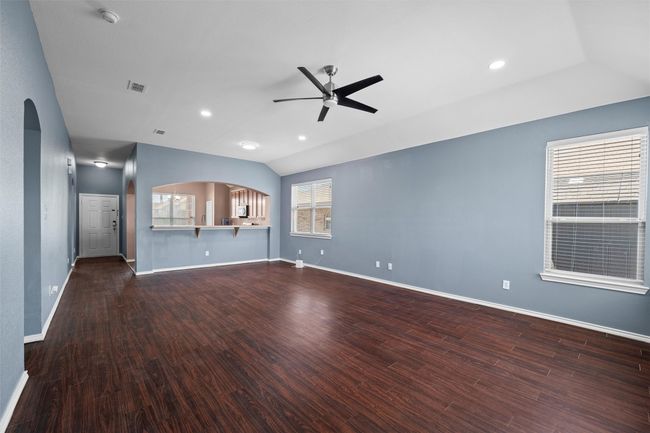 Unfurnished living room with arched walkways, baseboards, wood finished floors, and ceiling fan | Image 14
