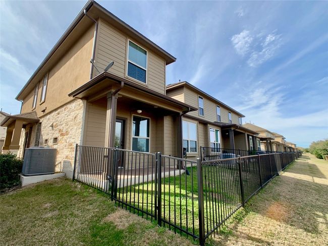 Rear view of property featuring central AC, stone siding, and covered porch | Image 9