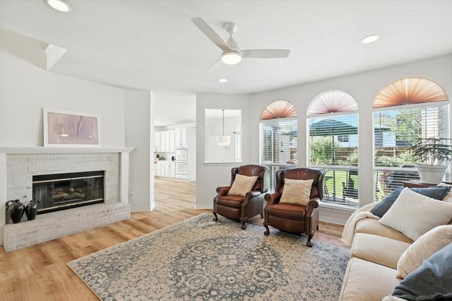 Living room with ceiling fan, wood finished floors, a fireplace, and recessed lighting | Image 11