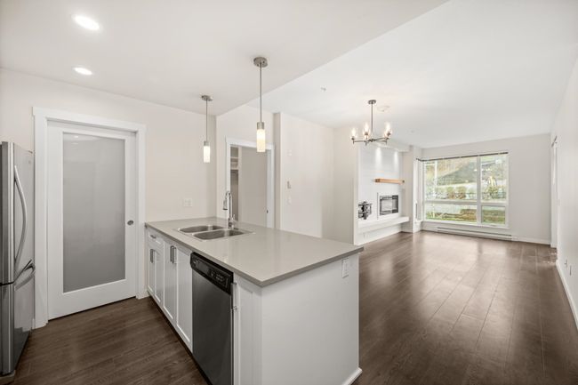 Kitchen featuring appliances with stainless steel finishes, a peninsula, dark wood-type flooring, a chandelier, and pendant lighting | Image 11