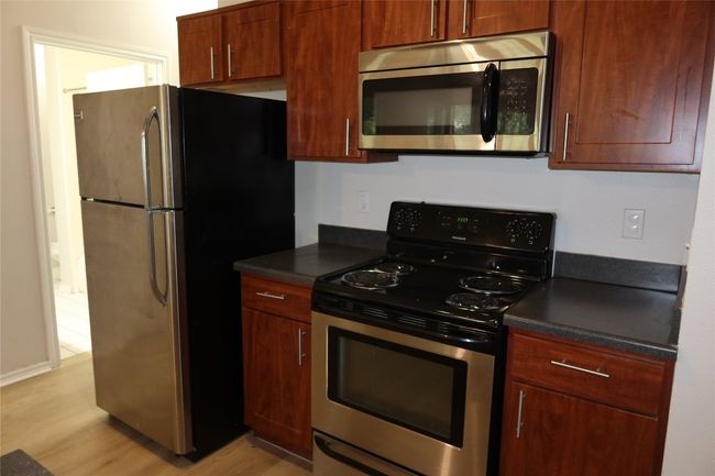 Kitchen featuring stainless steel appliances, dark countertops, and light wood-style floors | Image 7