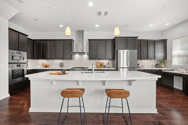 The large center island with a breakfast bar creates the perfect spot for casual meals, offering extra prep space while keeping you connected to the living and dining areas | Image 12