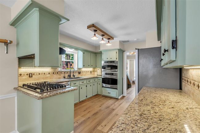 Upgraded kitchen with 5-burner gas cooktop, granite countertops and custom tile backsplash. | Image 18