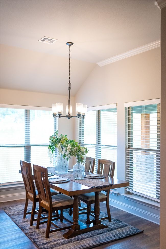 Dining room featuring an inviting chandelier, crown molding, vaulted ceiling, and dark wood finished floors | Image 12